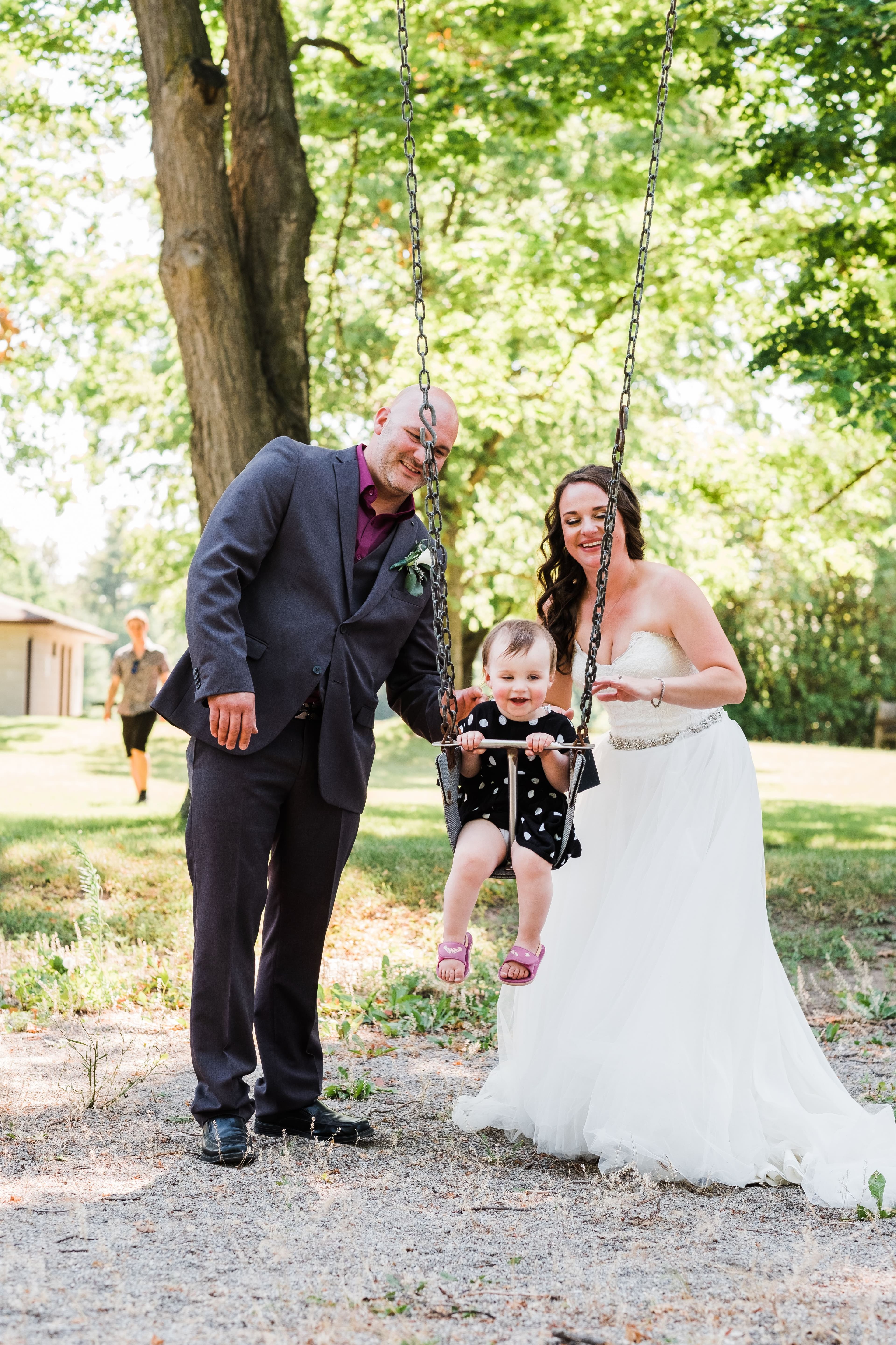 The wedding ring, Waterloo Regional Police Association, BMKH Photography, KW wedding photographer, Waterloo wedding venue, Kitchener wedding venue, Cambridge wedding venue, bride and groom and daughter on the swings in a park