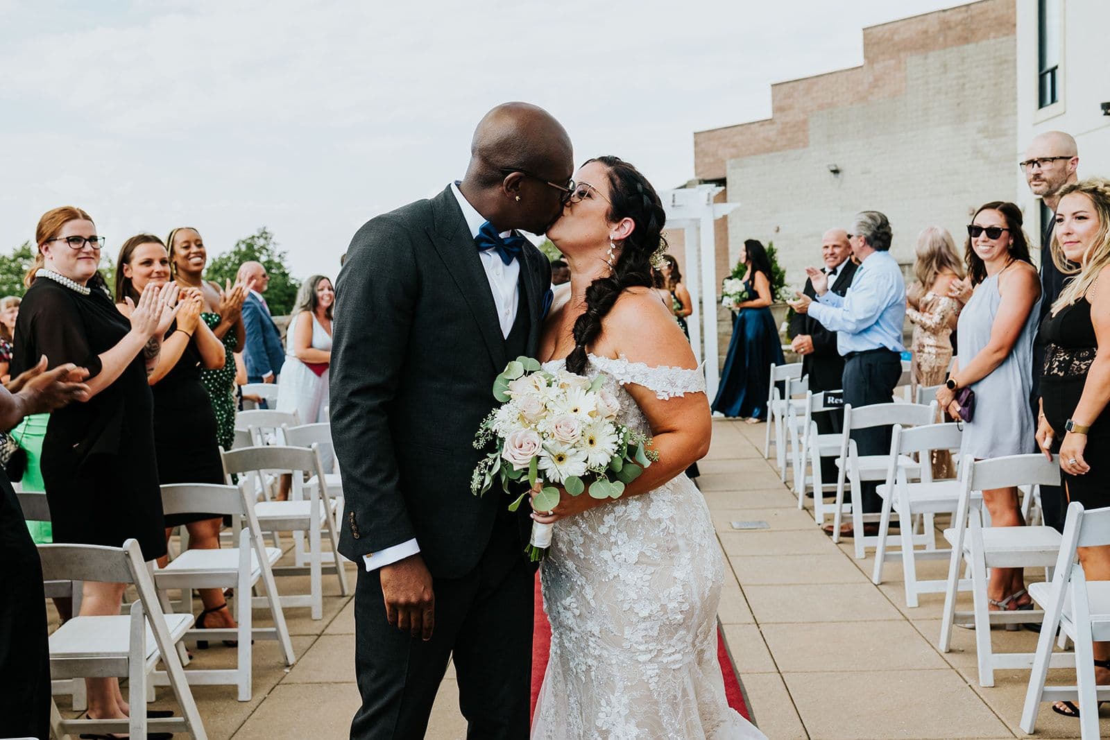 C Hotel by Carmen's, Hamilton wedding venue, Fedora Media, Cambridge wedding photographer, the wedding ring, bride and groom kissing at the end of aisle with guests cheering the background