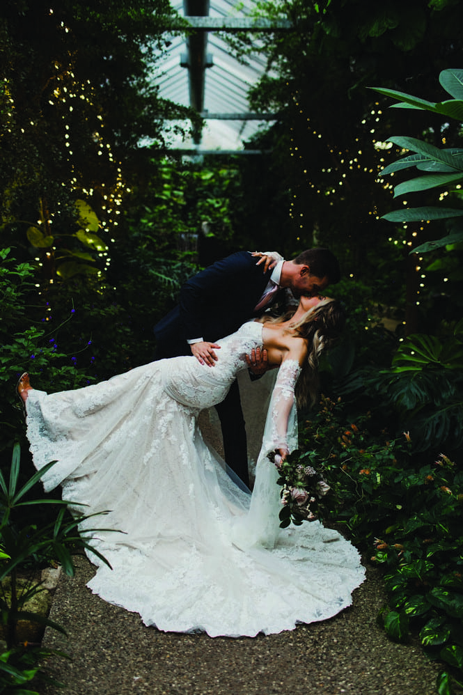groom dipping and kissing bride in boho wedding dress at cambridge butterfly conservatory