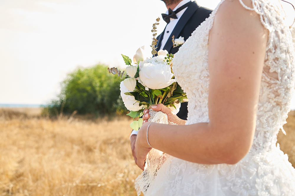 bride holding bouquet outside with groom at her side