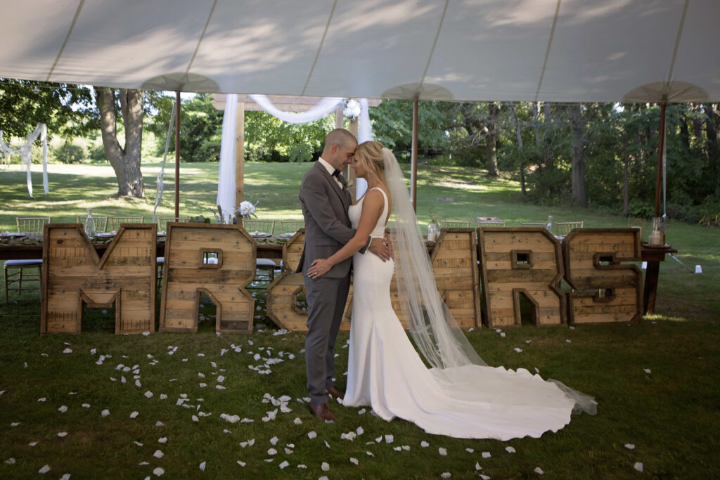 The wedding ring, Heart to heart photography, Thorold wedding photographer, wedding photographer, bride and groom kissing in wedding tent in front of big MR. & MRS. sign