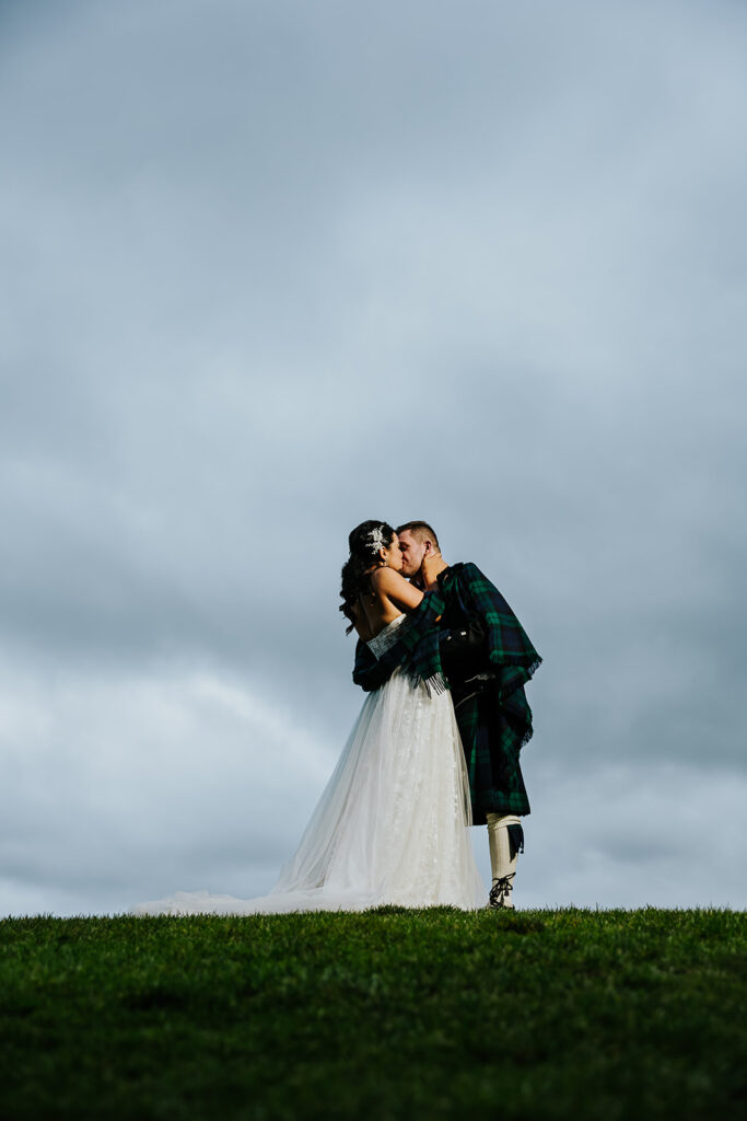 The Wedding Ring, Whistle Bear Golf Club, Wedding Venue, Kitchener Waterloo Wedding Venue, Fedora Media, Kitchener Wedding Photographer, Bride and Groom kissing at top of a hill with a cloudy sky in the background